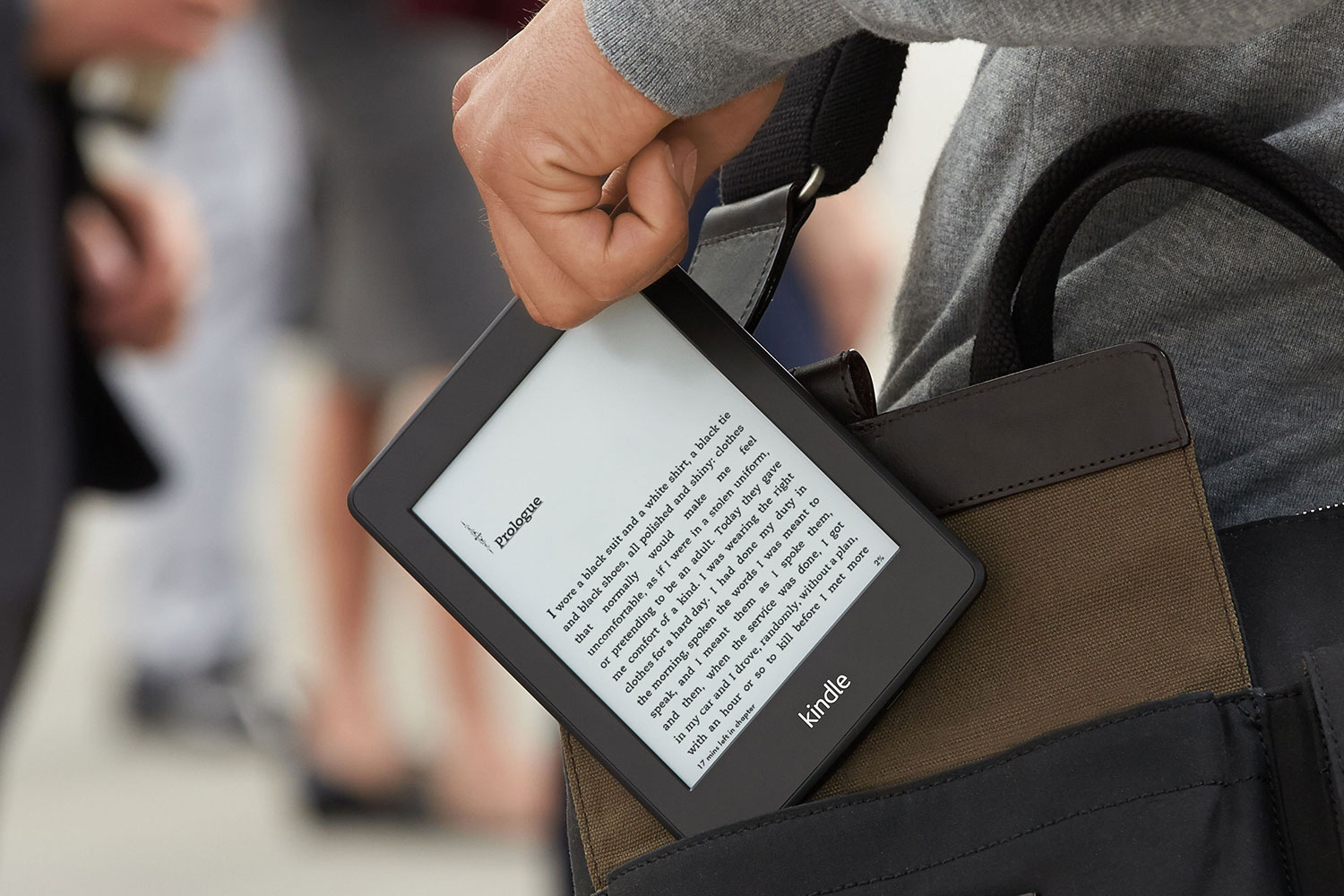 A close up of someone pulling a Kindle out of their bag.
